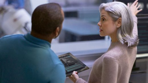 A woman holding a tablet with a man looking at it
