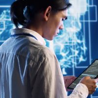 System administrator in data center running programming scripts on tablet, solving tasks. Experienced programmer manipulating lines of code for artificial intelligence applications development