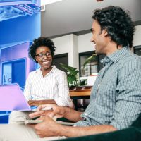 Two people on a security team sit at laptops together.