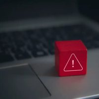 Red-warning-cube-on-a-laptop-keyboard Sicherheitslücke Alarm
