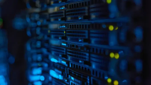 Server racks with illuminated indicators in a dimly lit data center.
