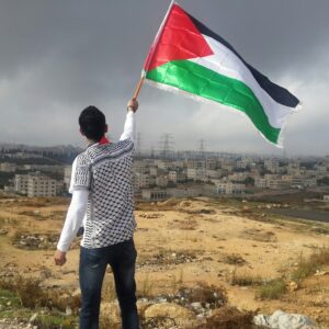 Man holding palestine flag over cityscape wallpaper