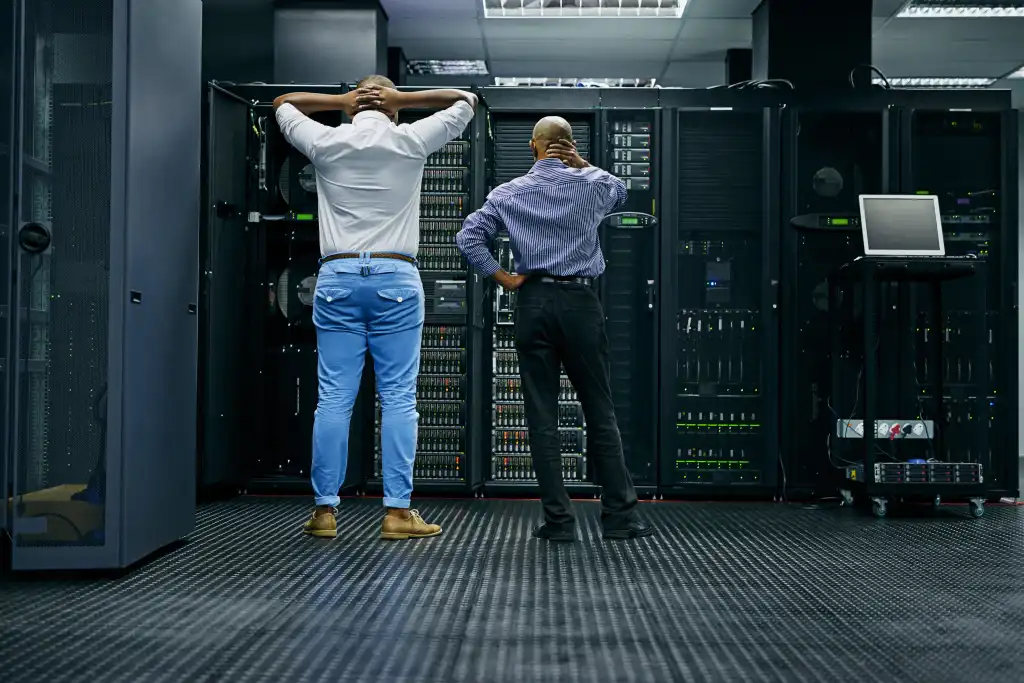 Meanwhile in the server room.... Rearview shot of two IT technicians having difficulty repairing a computer in a data center.