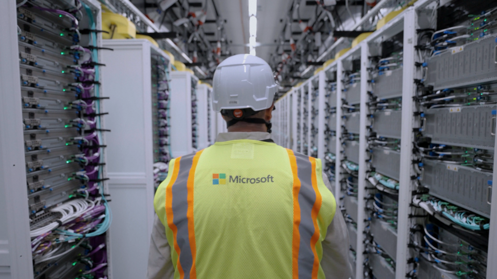 An employee standing between server racks at a Microsoft AI datacenter.