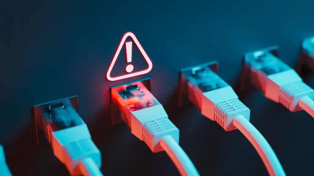 A photograph of a row of Ethernet cables plugged into ports, with a warning sign illuminated above one of the ports.