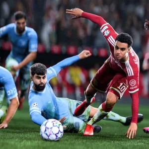 Players in sky blue and red fall around a loose ball during a goalmouth scramble