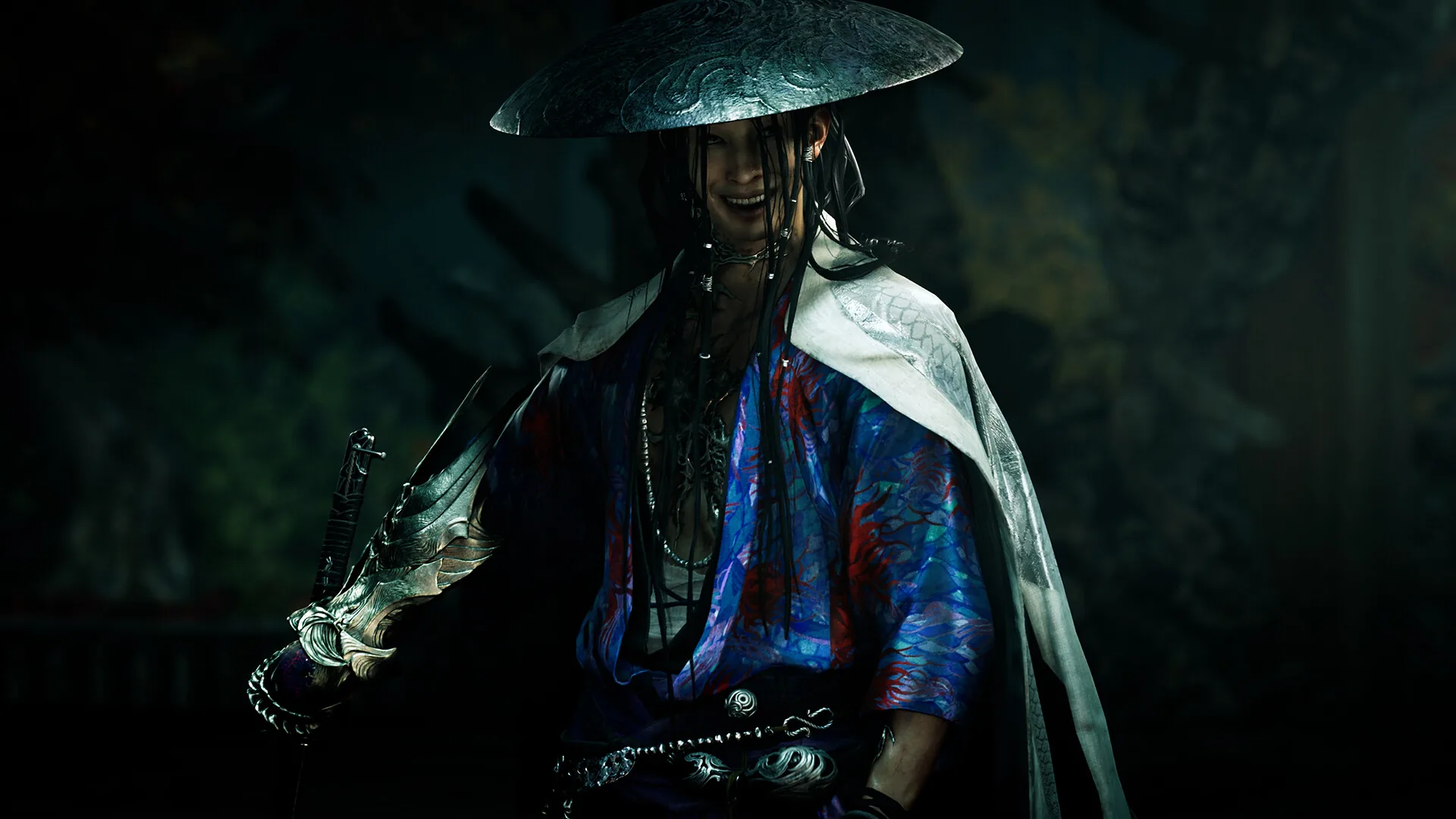 A smiling swordsman in a wide metal hat and a blue and red patterned robe stands in shadow
