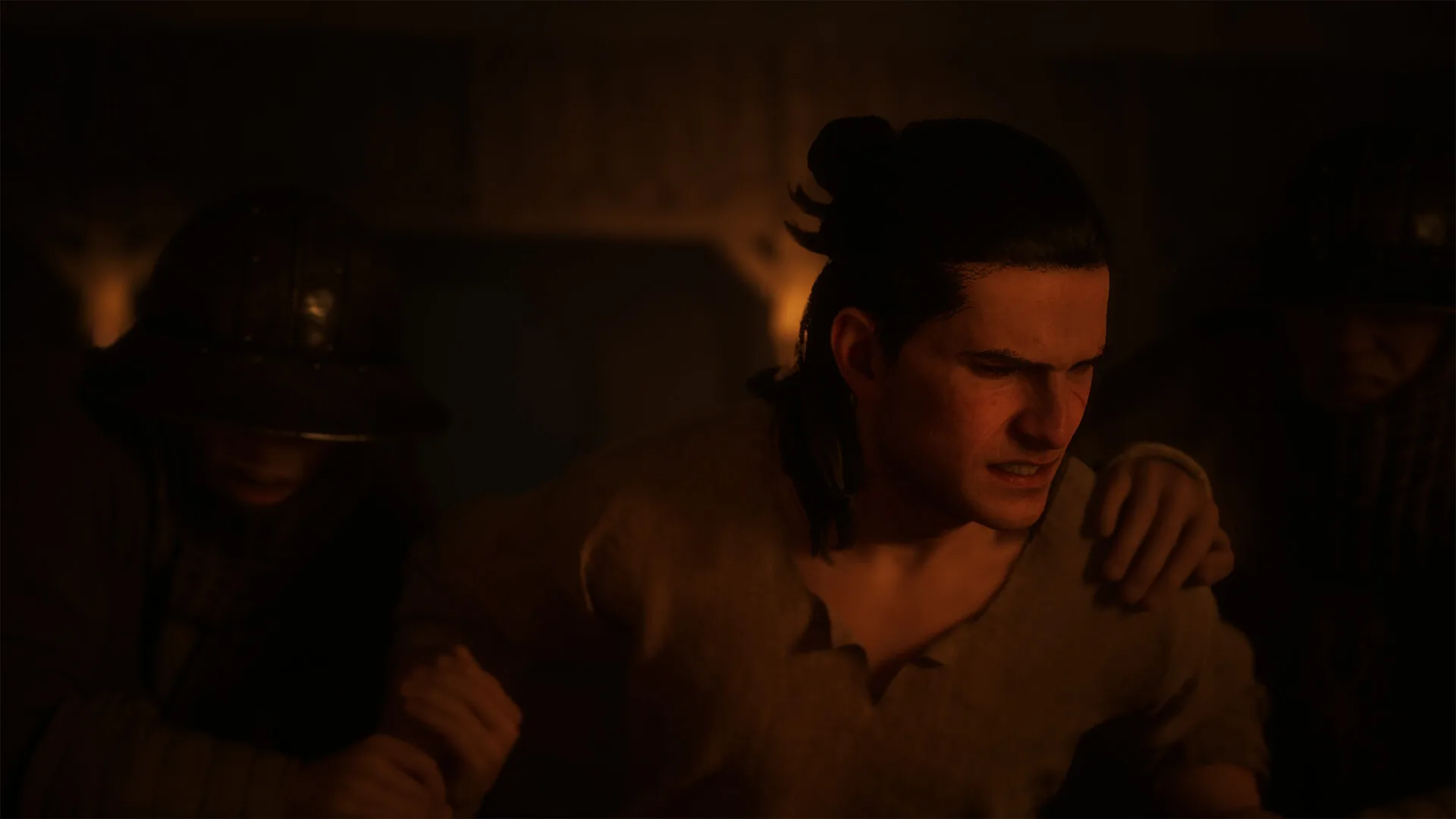 Coen comforting a wounded man in a dim interior in The Blood of Dawnwalker