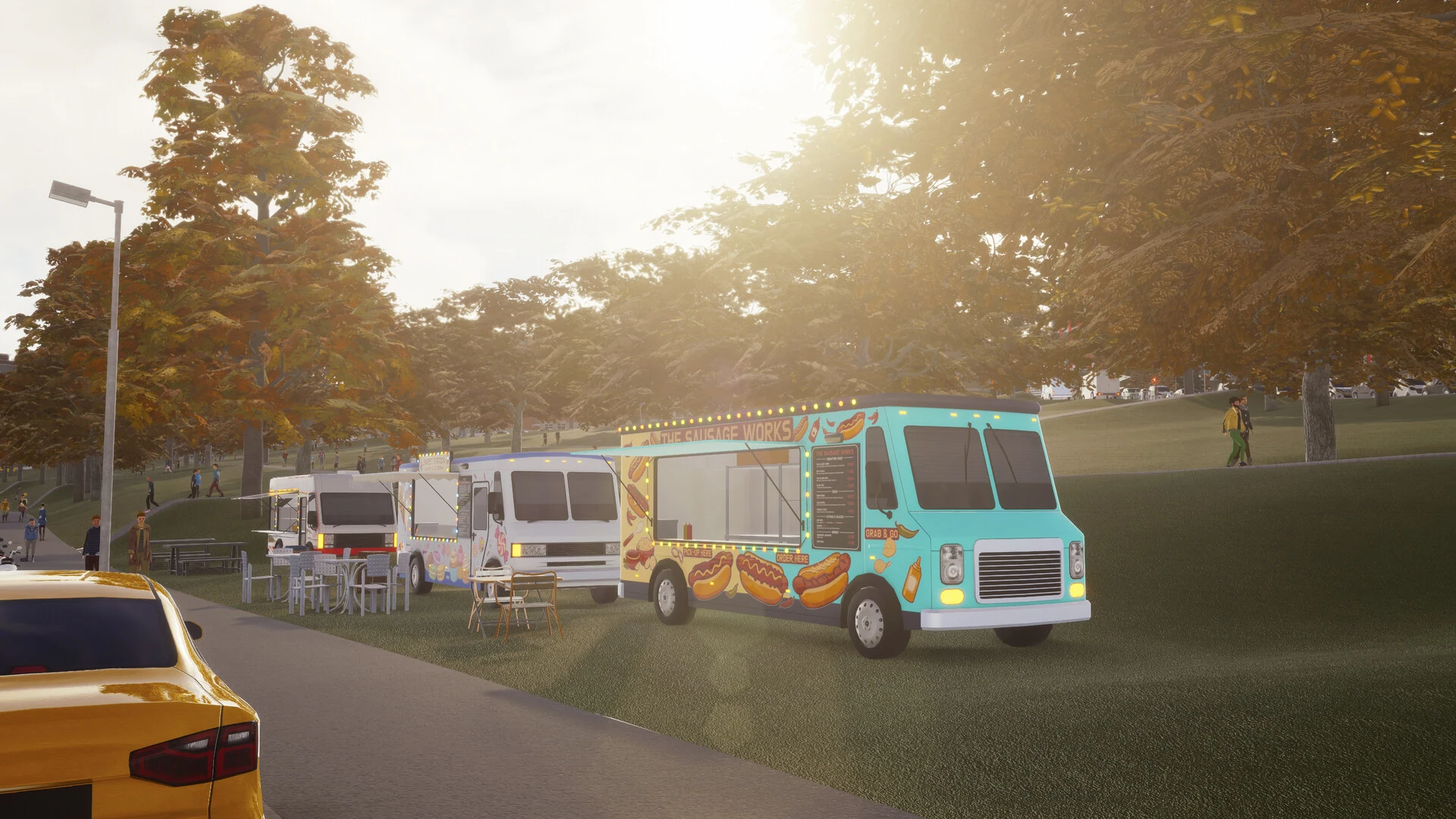 Colorful food trucks parked on grass beside a road in warm evening light