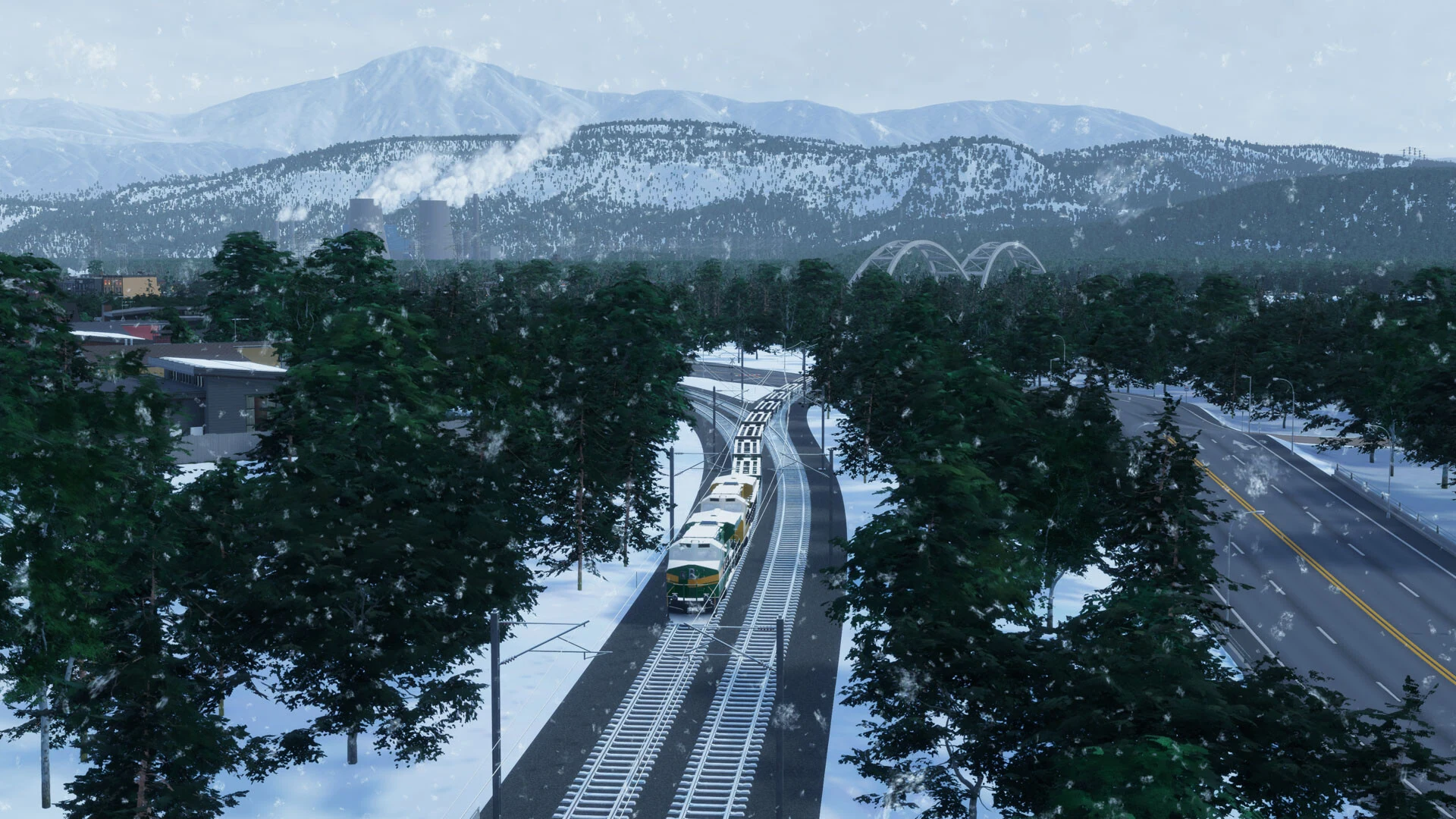 A passenger train runs through a snowy forest beside a highway, with snow-covered mountains in the distance