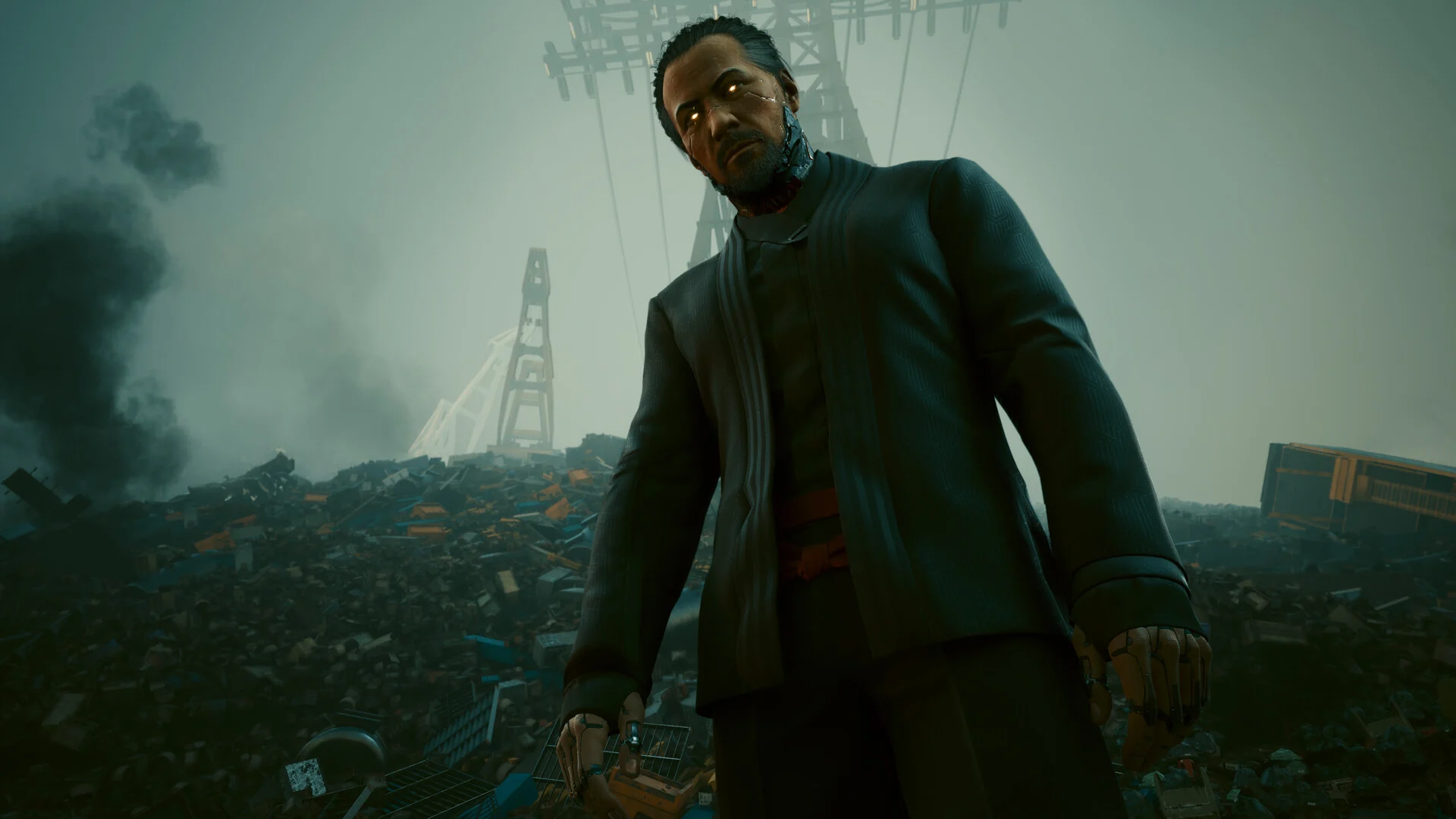 A man in a dark suit walks out of drifting smoke on a misty industrial lot