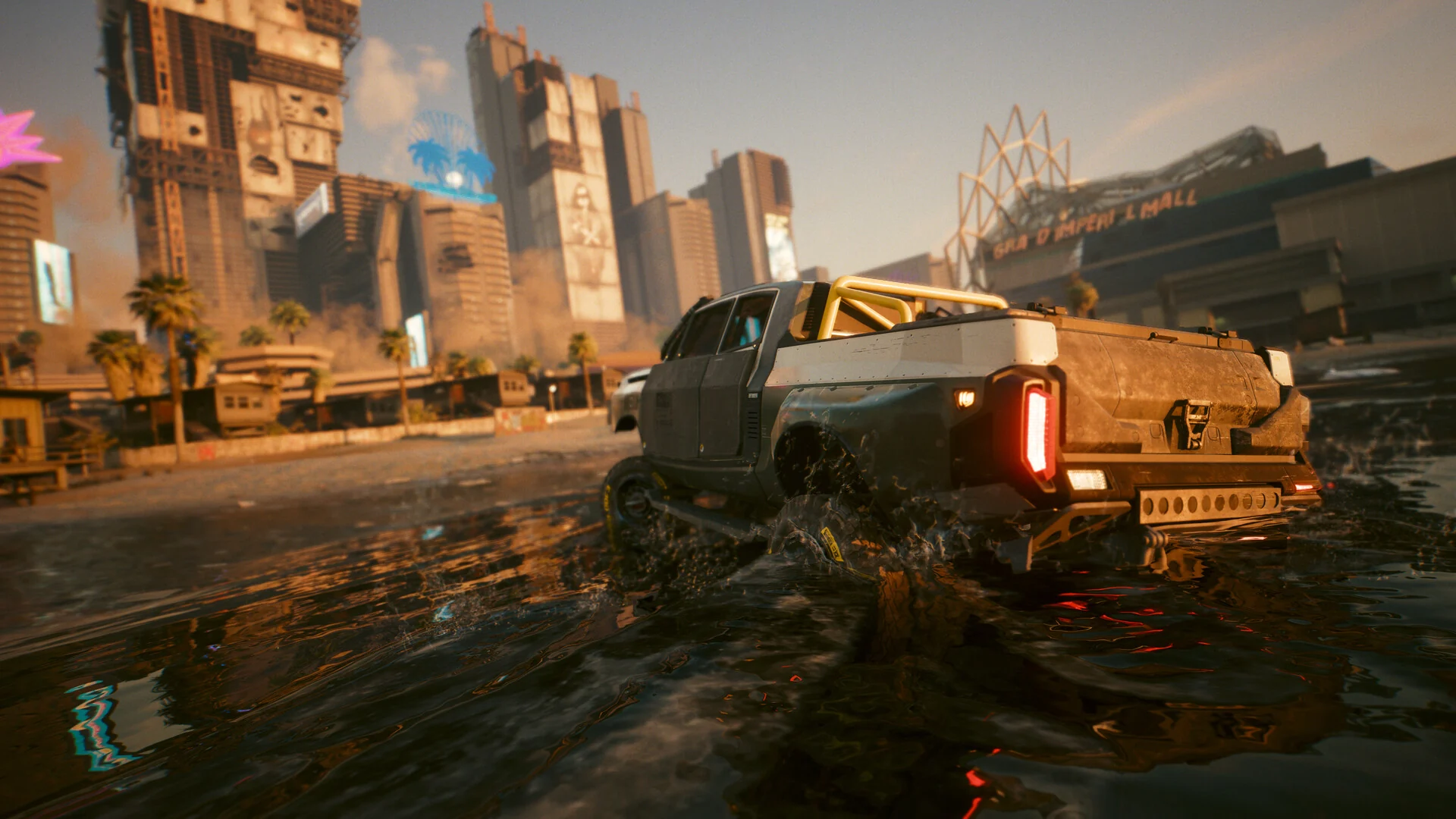 A rugged pickup truck splashes through a flooded street at sunset, with the city behind it