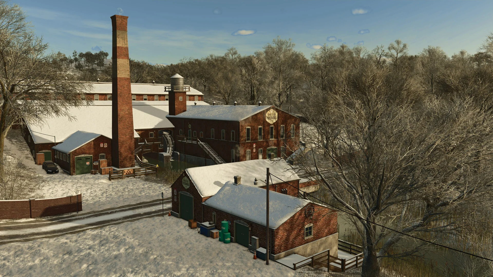 A snowy red brick factory with a tall chimney among bare winter trees in Farming Simulator 25