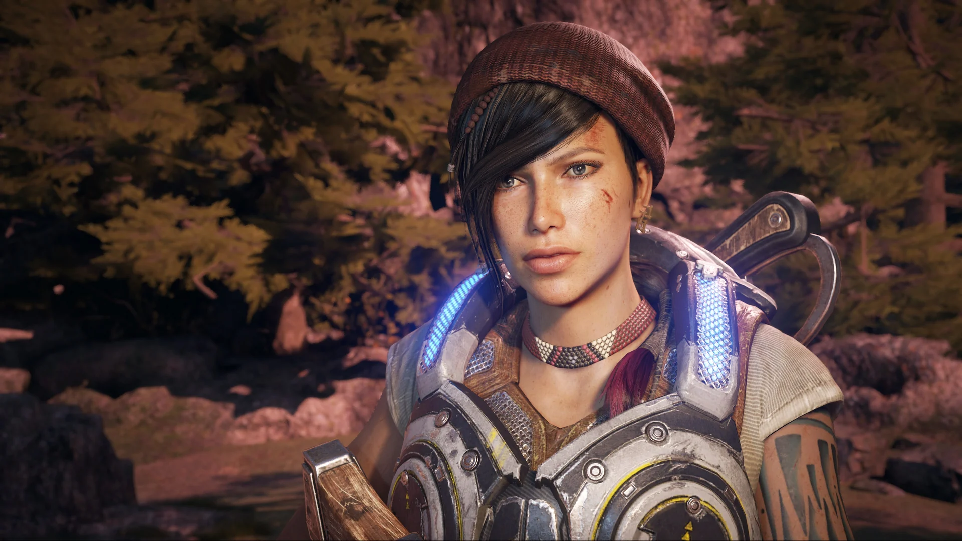 Kait Diaz in a red beanie and COG armor stands in a forest at dusk