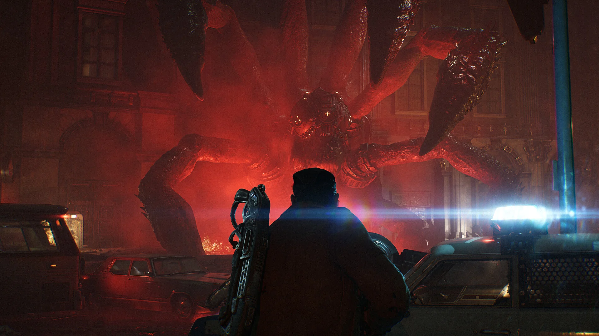 A soldier with a rifle on his back faces a giant many-legged creature bursting out of a street lit in red