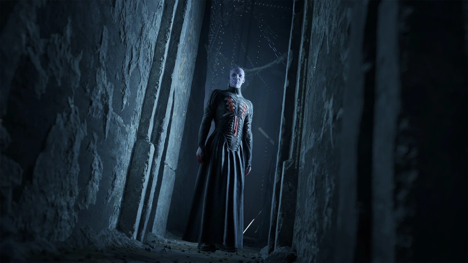 Pinhead, the Hell Priest, stands in a tall stone doorway in Hellraiser: Revival, watching the player from the shadows