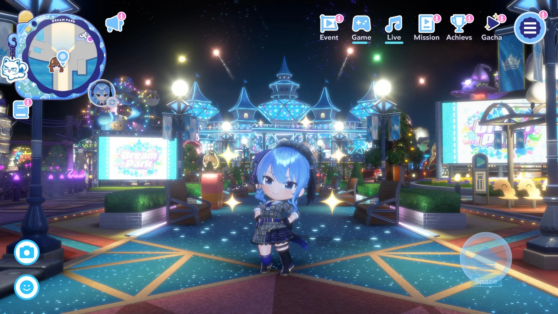 A chibi hololive member with blue hair stands in the Dream Park theme park at night, with lit castles, video screens and the park map in the corner