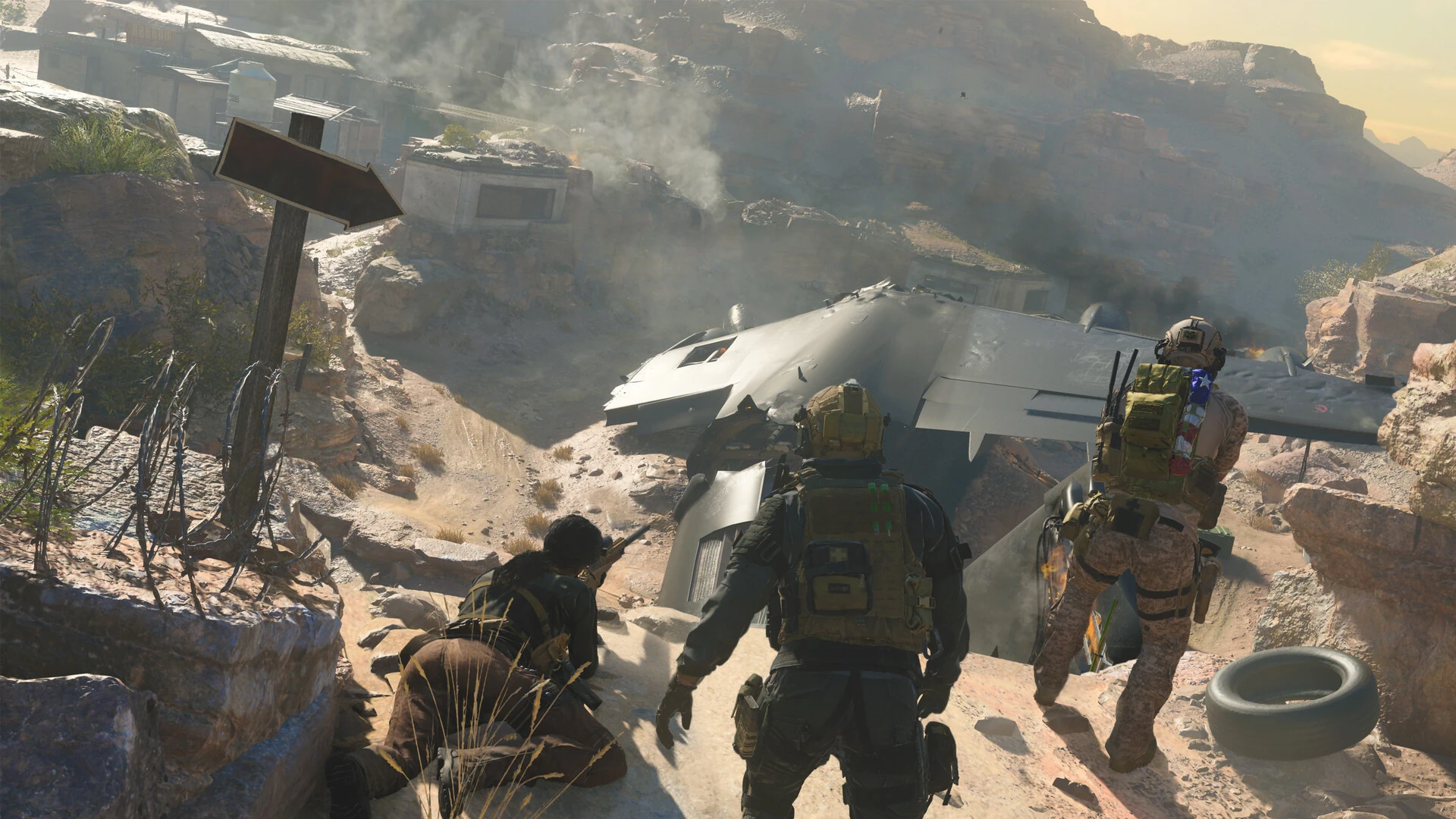 Soldiers advance through a rocky desert past the wreck of a crashed aircraft
