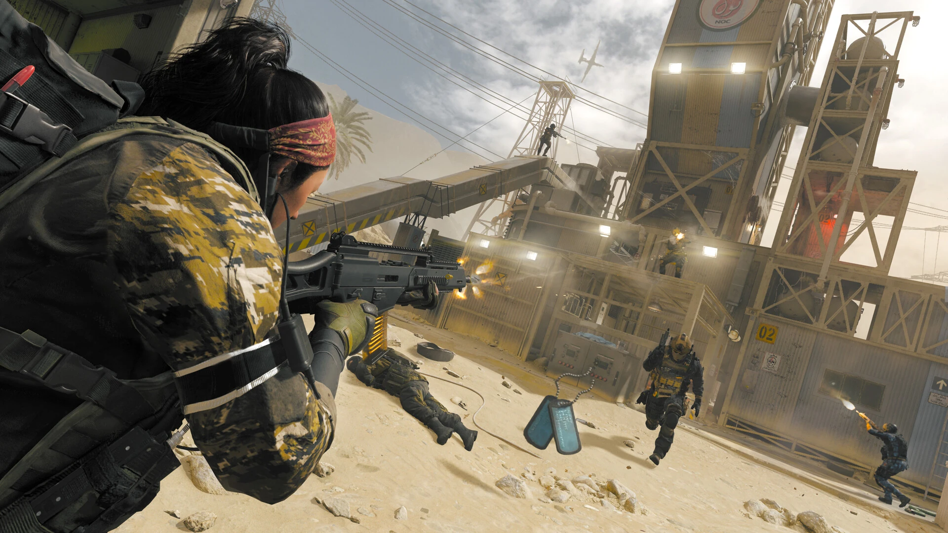A player sprints and fires across a sandy yard below a rusted oil derrick as enemies shoot back
