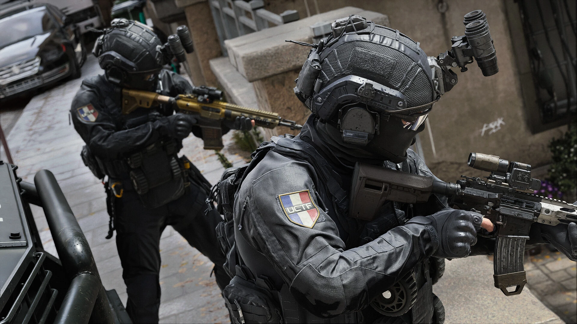 Two operators in black tactical helmets with French flag patches aim rifles beside an armored vehicle on a city street