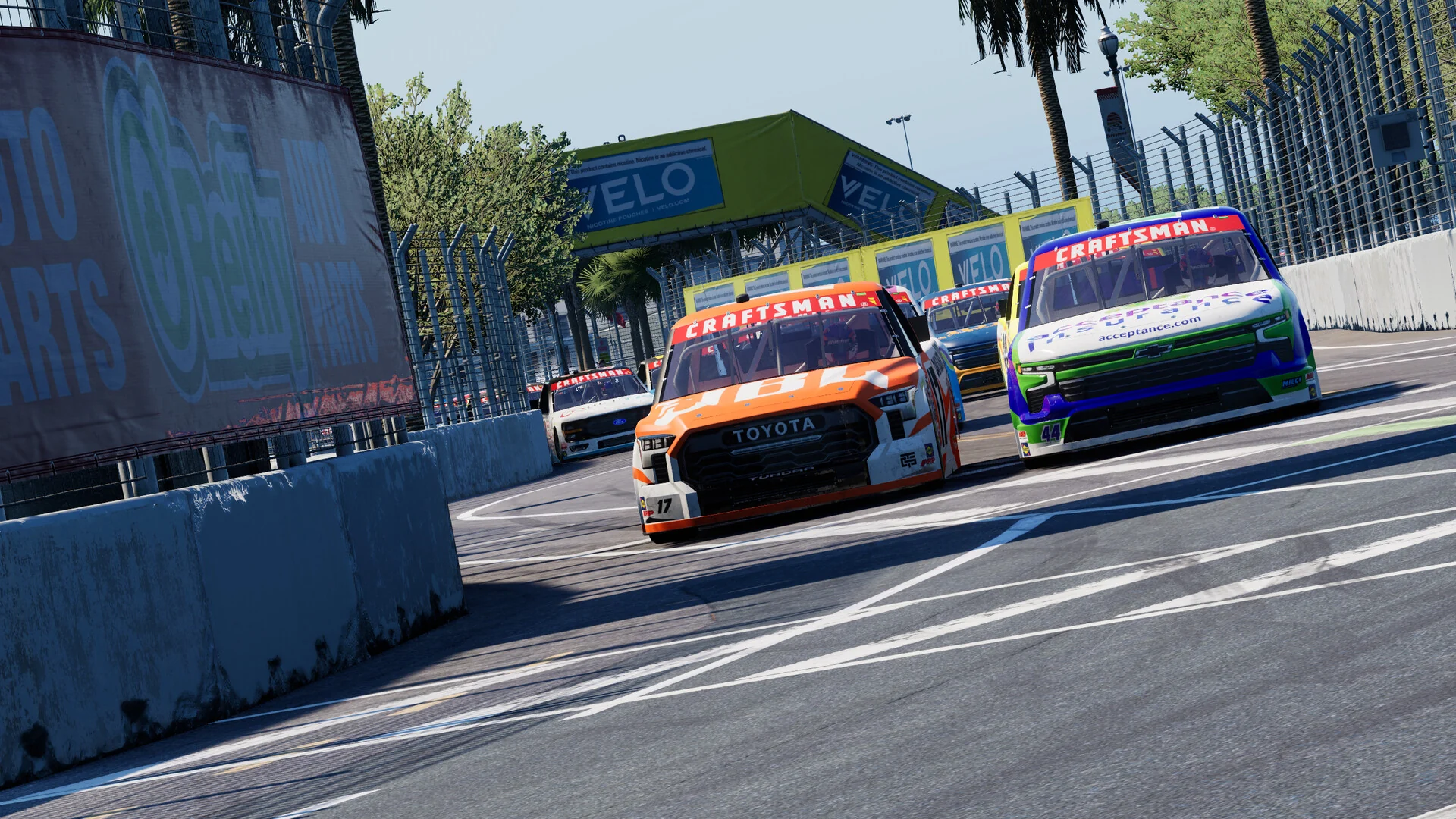 Two Craftsman Truck Series pickups battle side by side through a corner of the St. Petersburg street circuit lined with palm trees