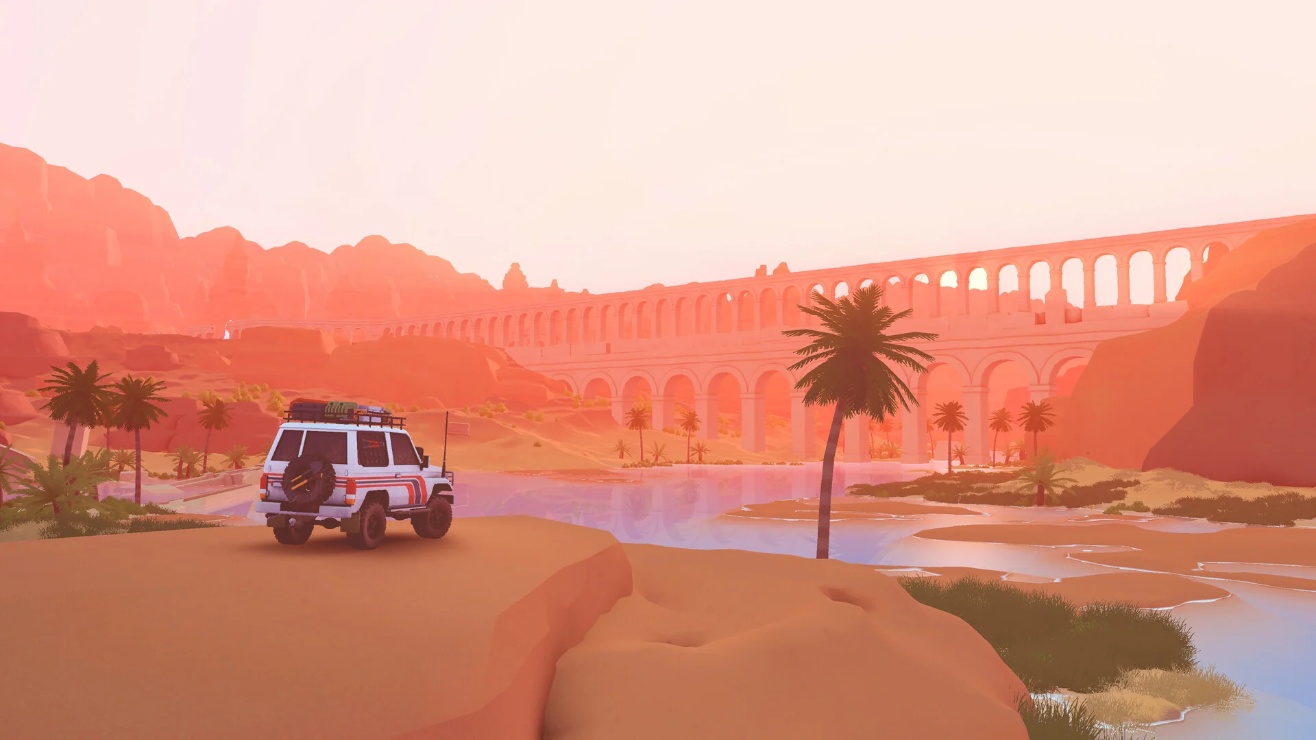 A white 4x4 drives past palm trees toward an old stone aqueduct in a desert canyon at sunset
