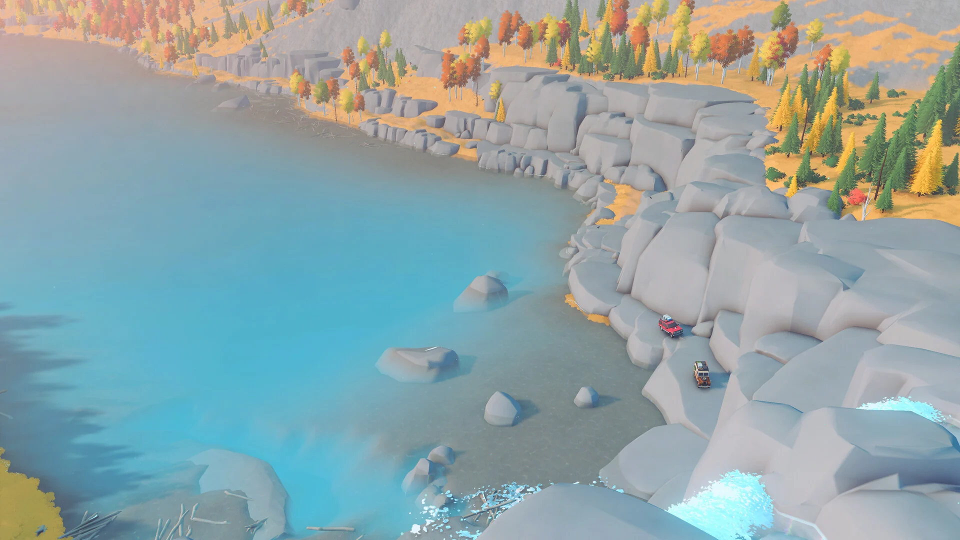 High view of 4x4s winding over grey rock slabs beside a bright blue lake and autumn forest