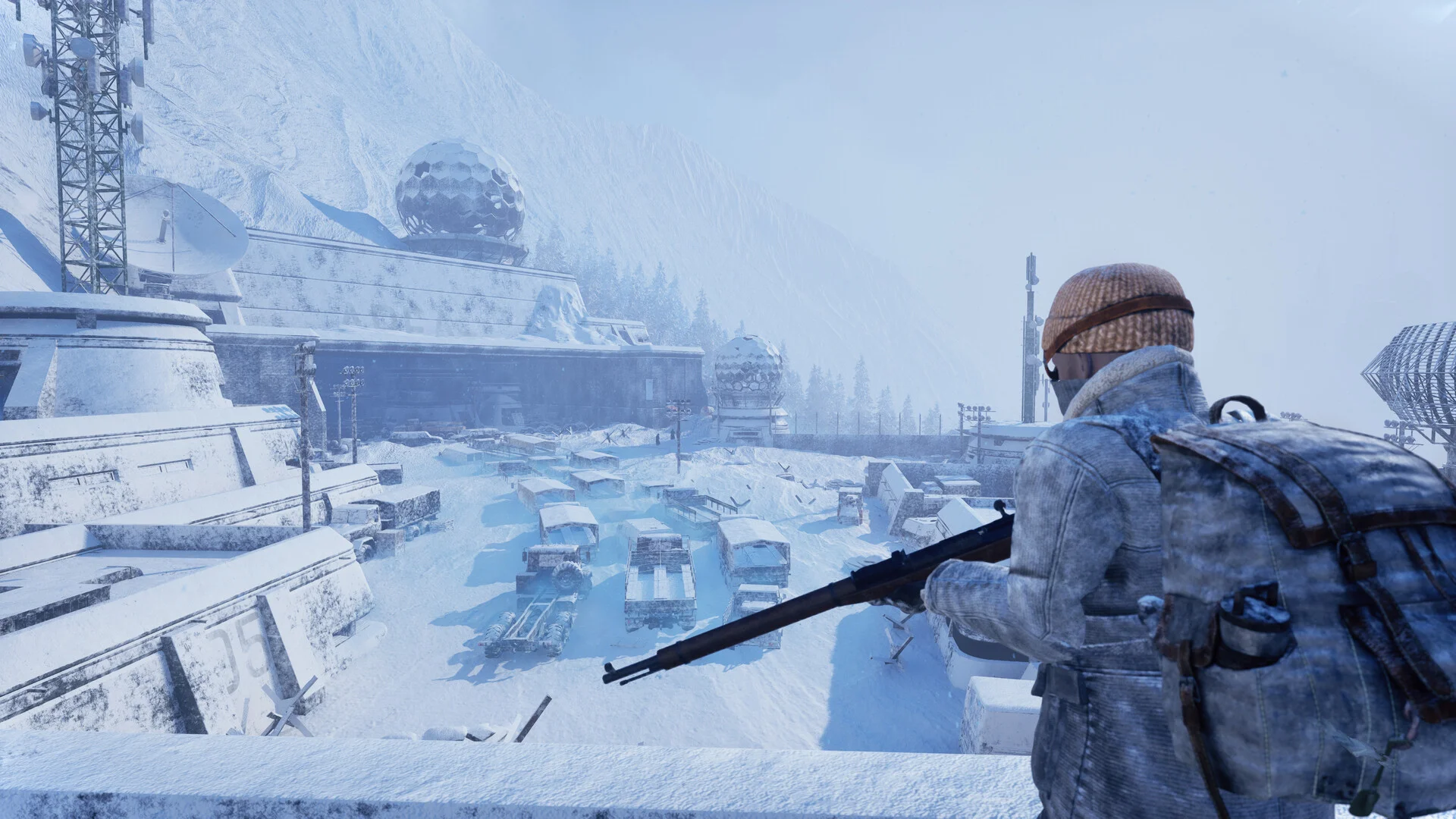 A survivor in a knit hat holds a bolt-action rifle on a snowy ridge above a frozen observatory and parking lot