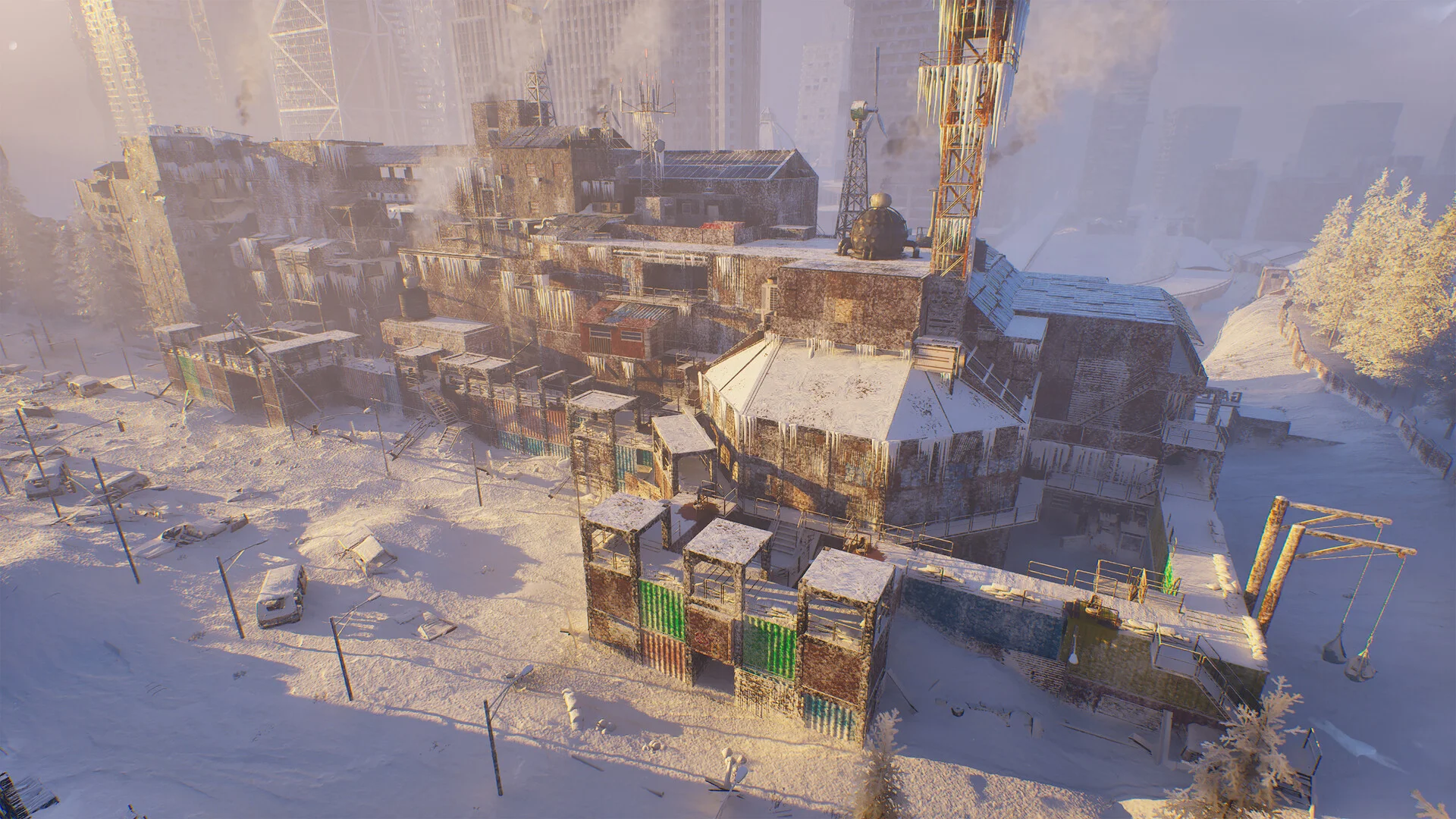 A fortified settlement built from shipping containers and scrap wood glows in low evening sun on a snowy hillside