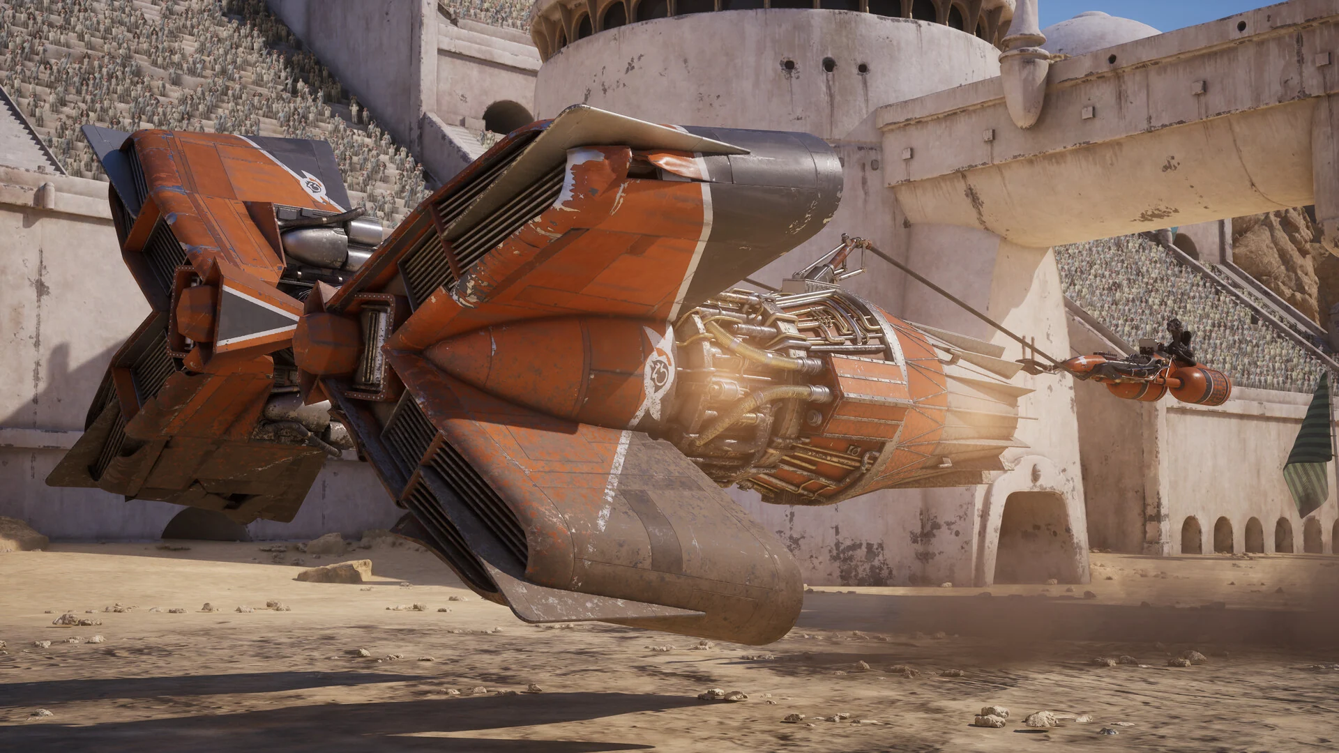 An orange podracer launches past the grandstands of a sandstone arena at the start of a race