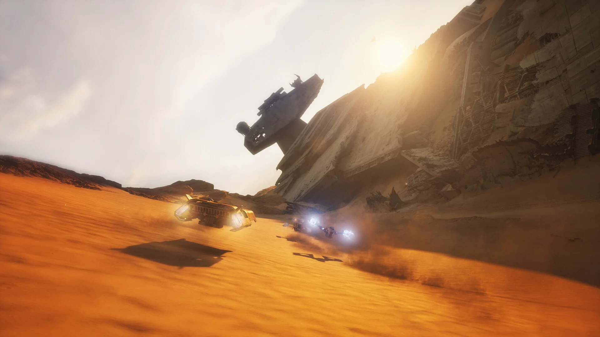 Landspeeders race low over orange sand dunes past the wreck of a crashed Star Destroyer