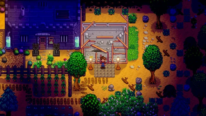 A farm at night with lanterns, crops and a run-down greenhouse waiting to be repaired in Stardew Valley