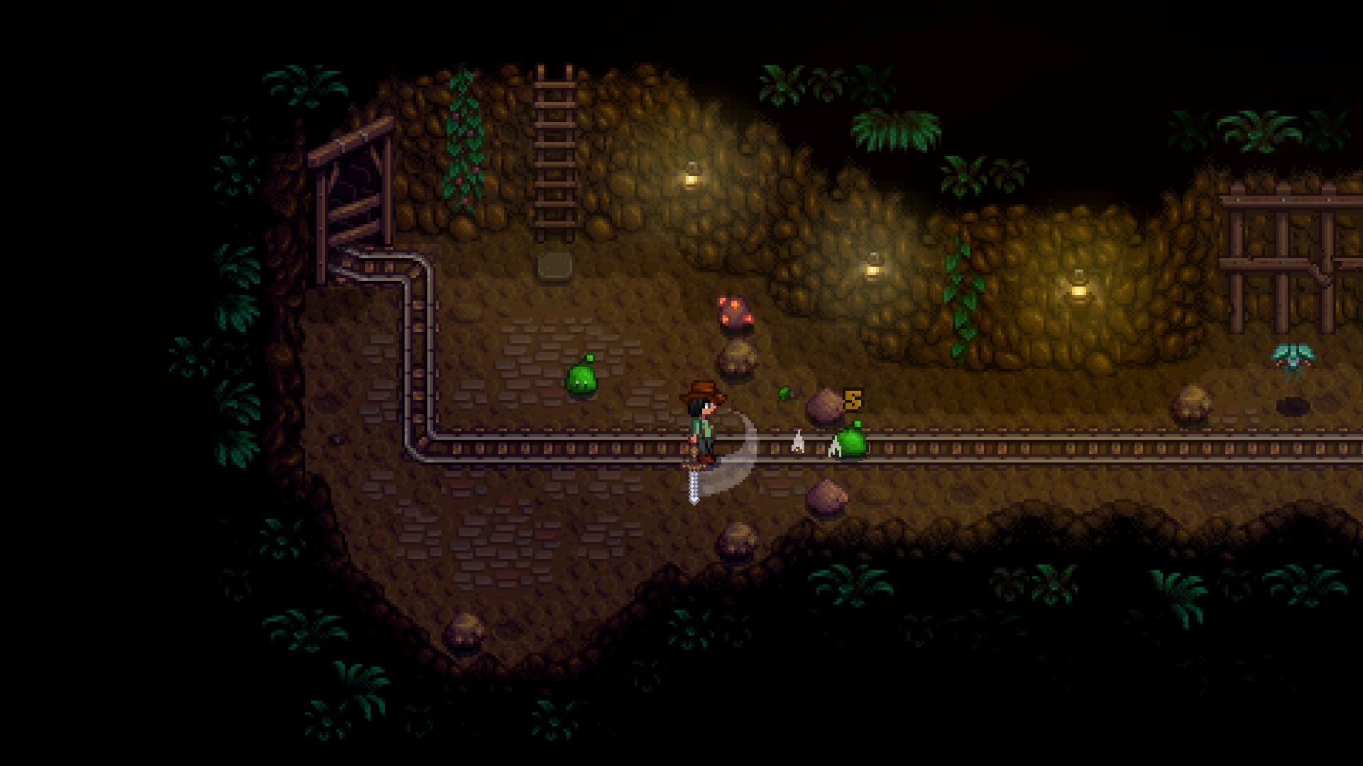 The player swings a sword at a green slime in a dark cave level of the mines in Stardew Valley, with minecart rails along the wall