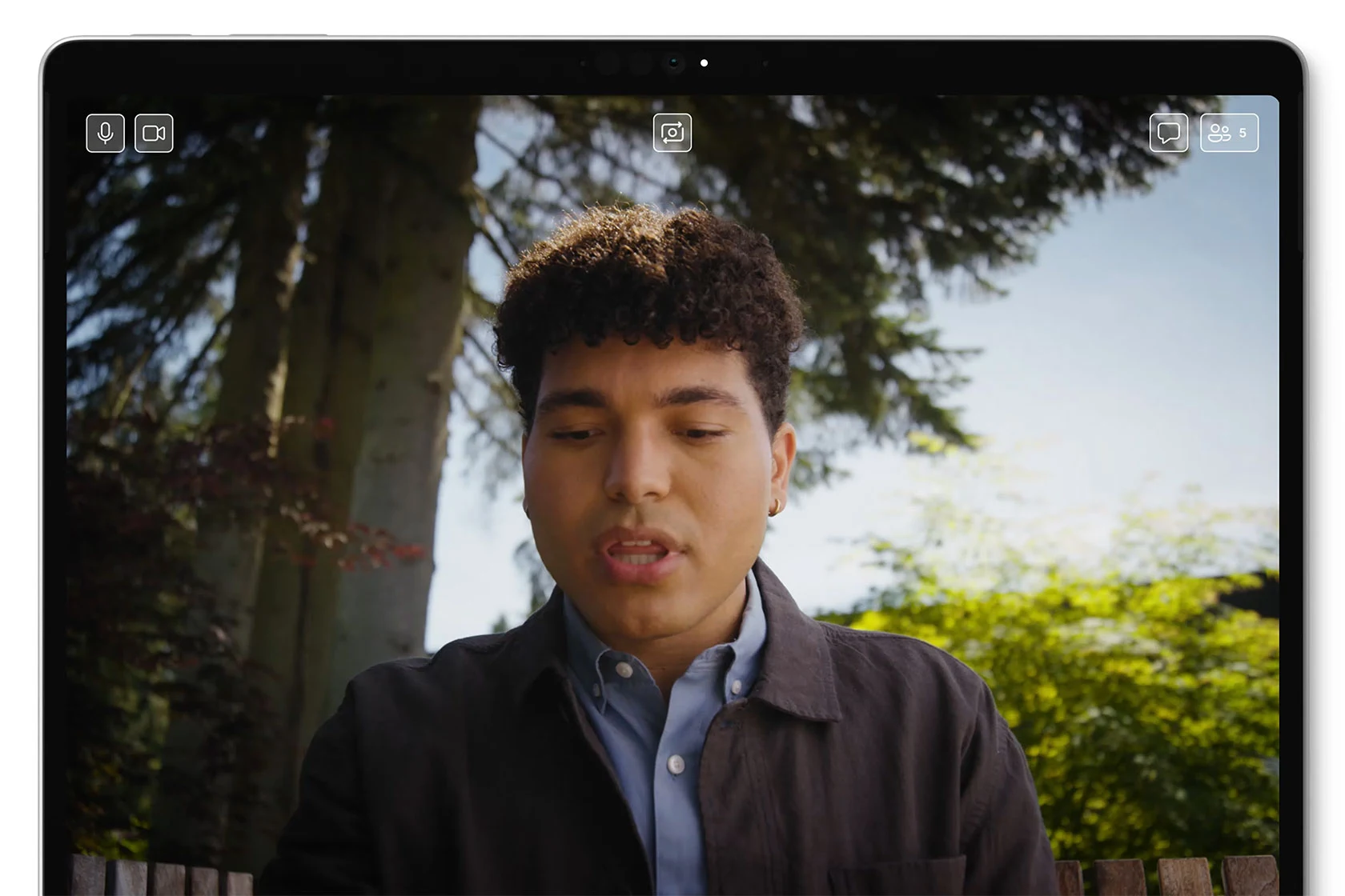 A young man on a video call shown full screen on a Surface Pro, framed by the front camera