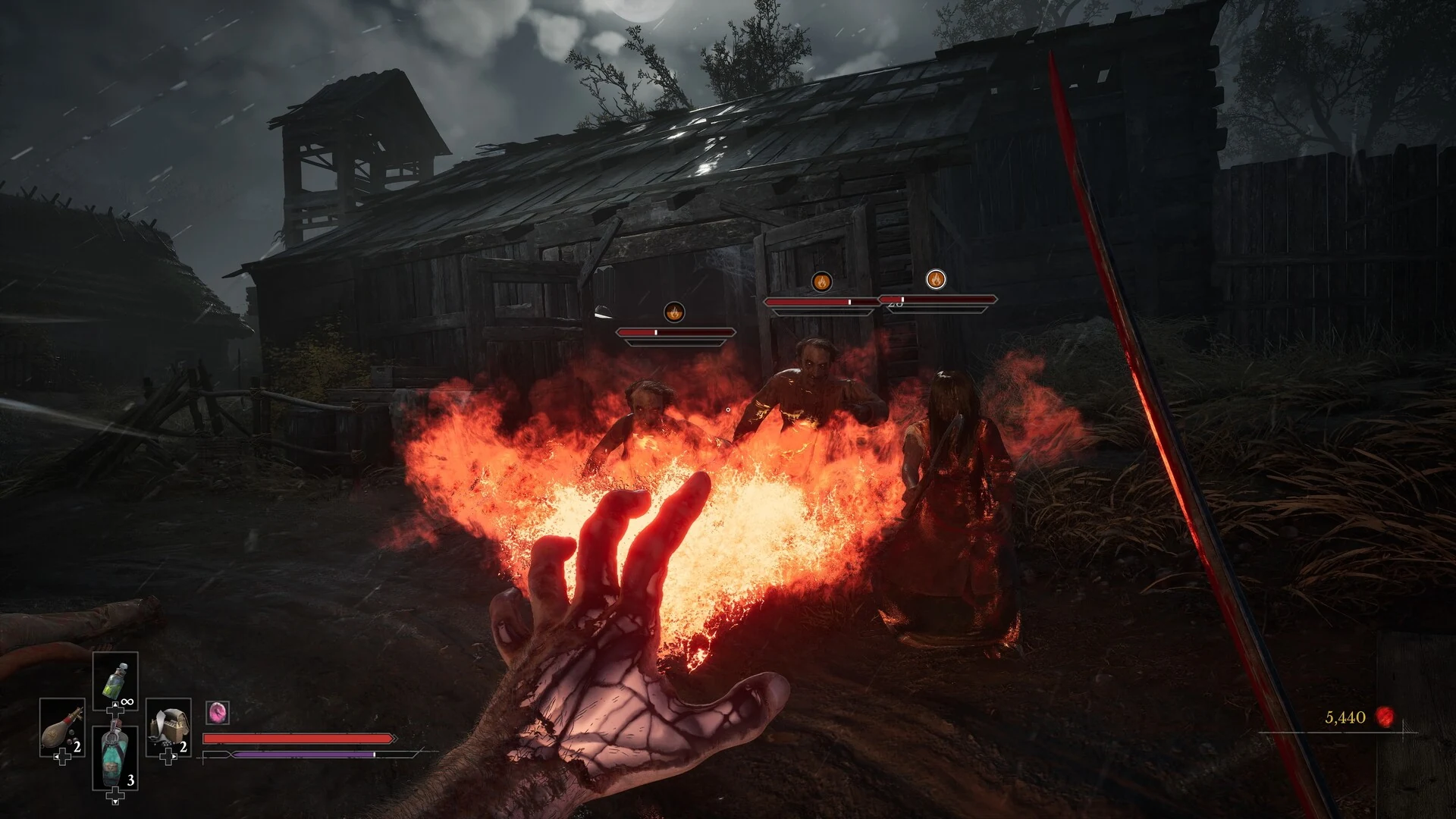 The player's left hand glows with veins of red light as it throws a burst of fire beside a dark wooden barn